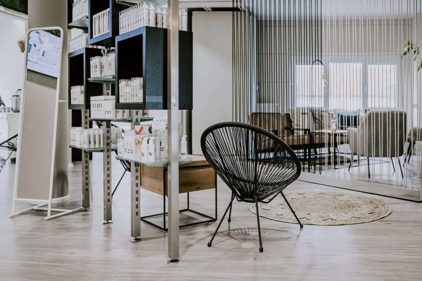 Empfangsbereich mit Produktregal, schwarzem Sessel und Lounge im Hintergrund