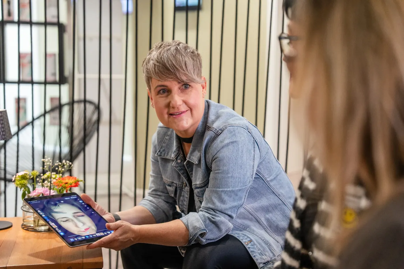 Kosmetikerin zeigt einer Kundin im Gespräch die Aufnahmen auf dem Tablet