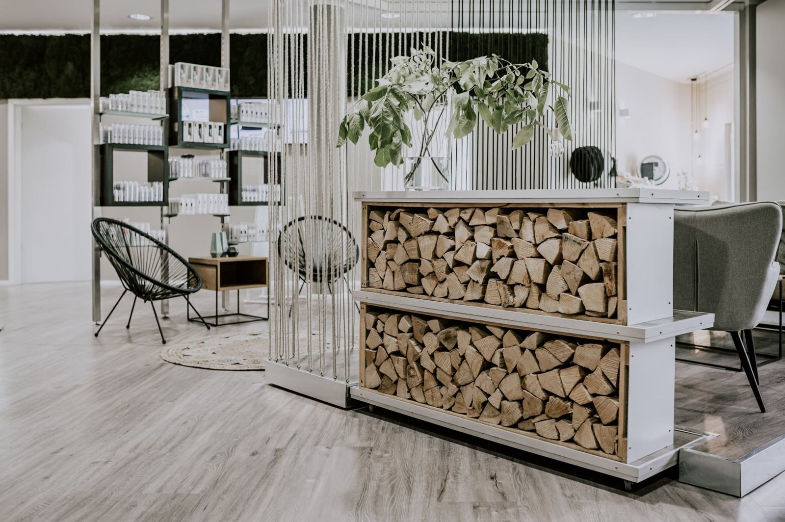 Regal mit Holzscheiten, Kordelvorhang und Sessel am Empfang